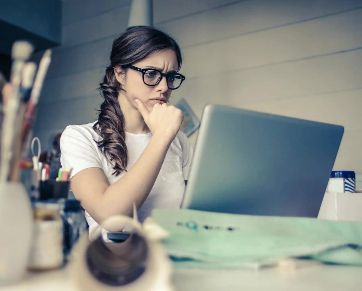 Student thinking while working on a laptop