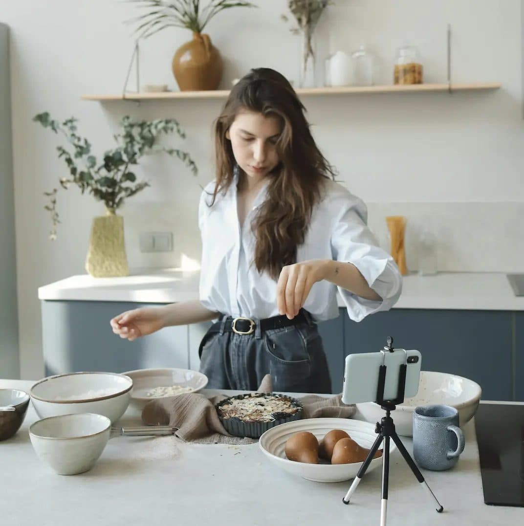 Creator filming a cooking video on her phone in a kitchen