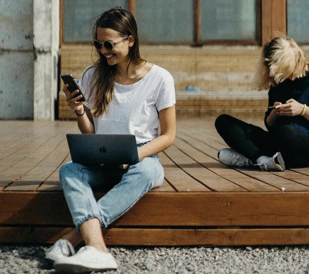 Student working on a laptop and phone outdoors