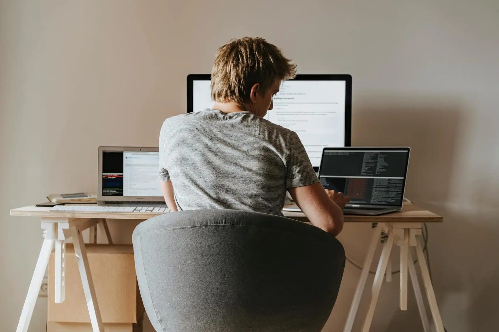 Student web developer coding at a desk with two screens